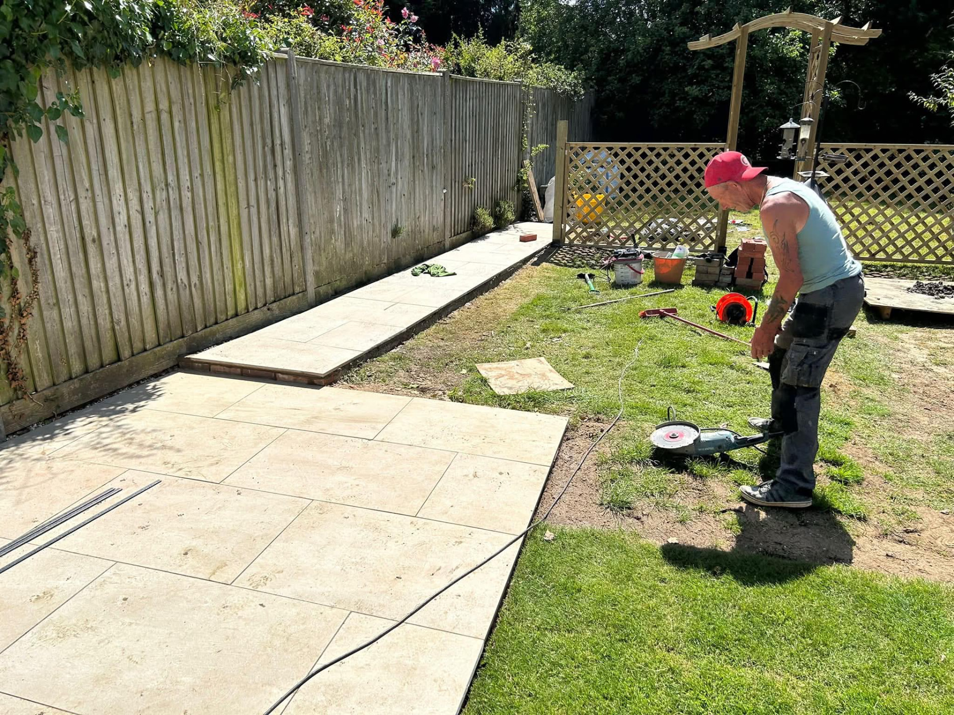 Landscaper cutting paving slabs beside a freshly laid path and lawn in a Berkshire garden